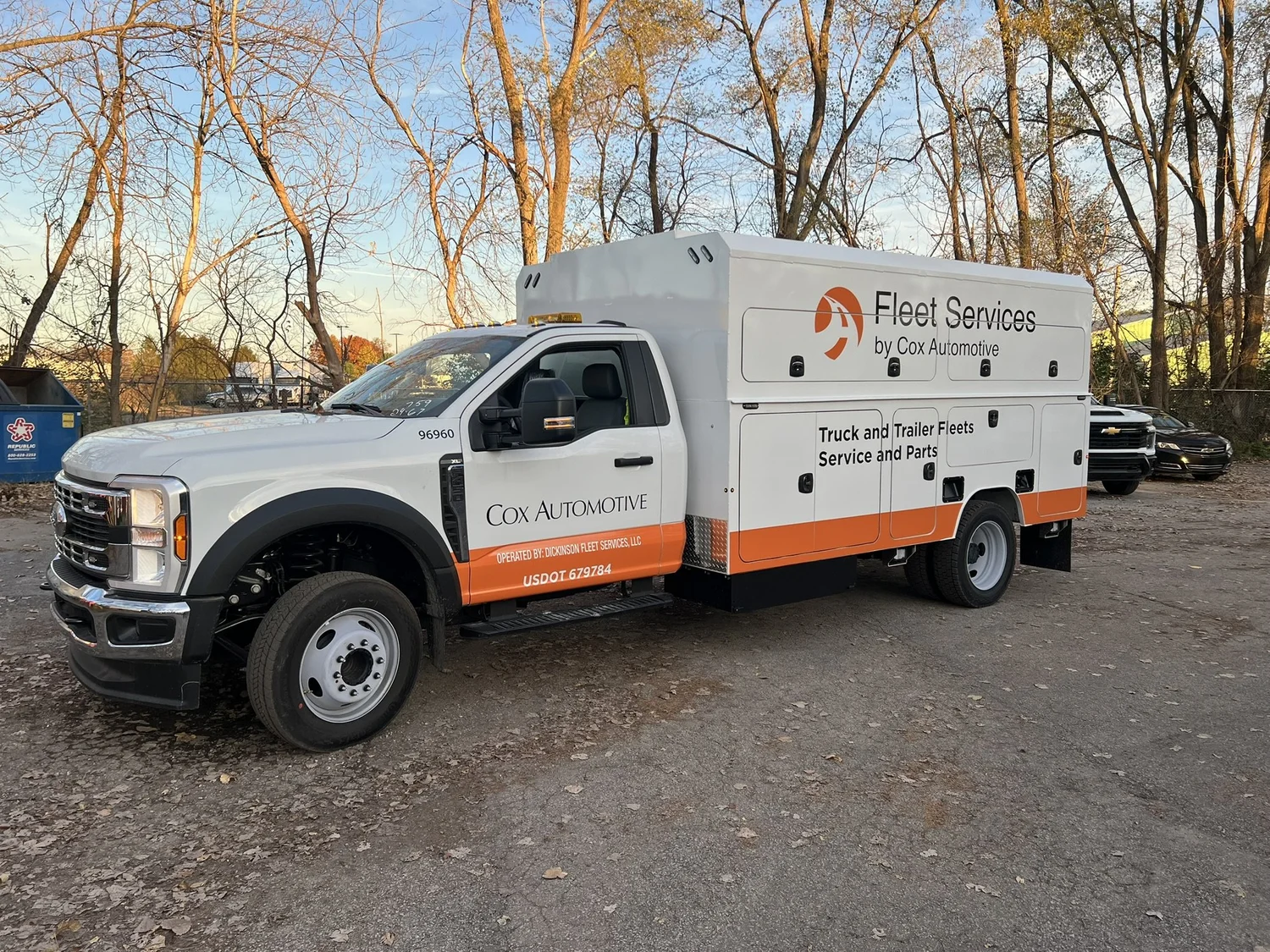 A white and orange Cox Automotive service truck with coordinated company graphics