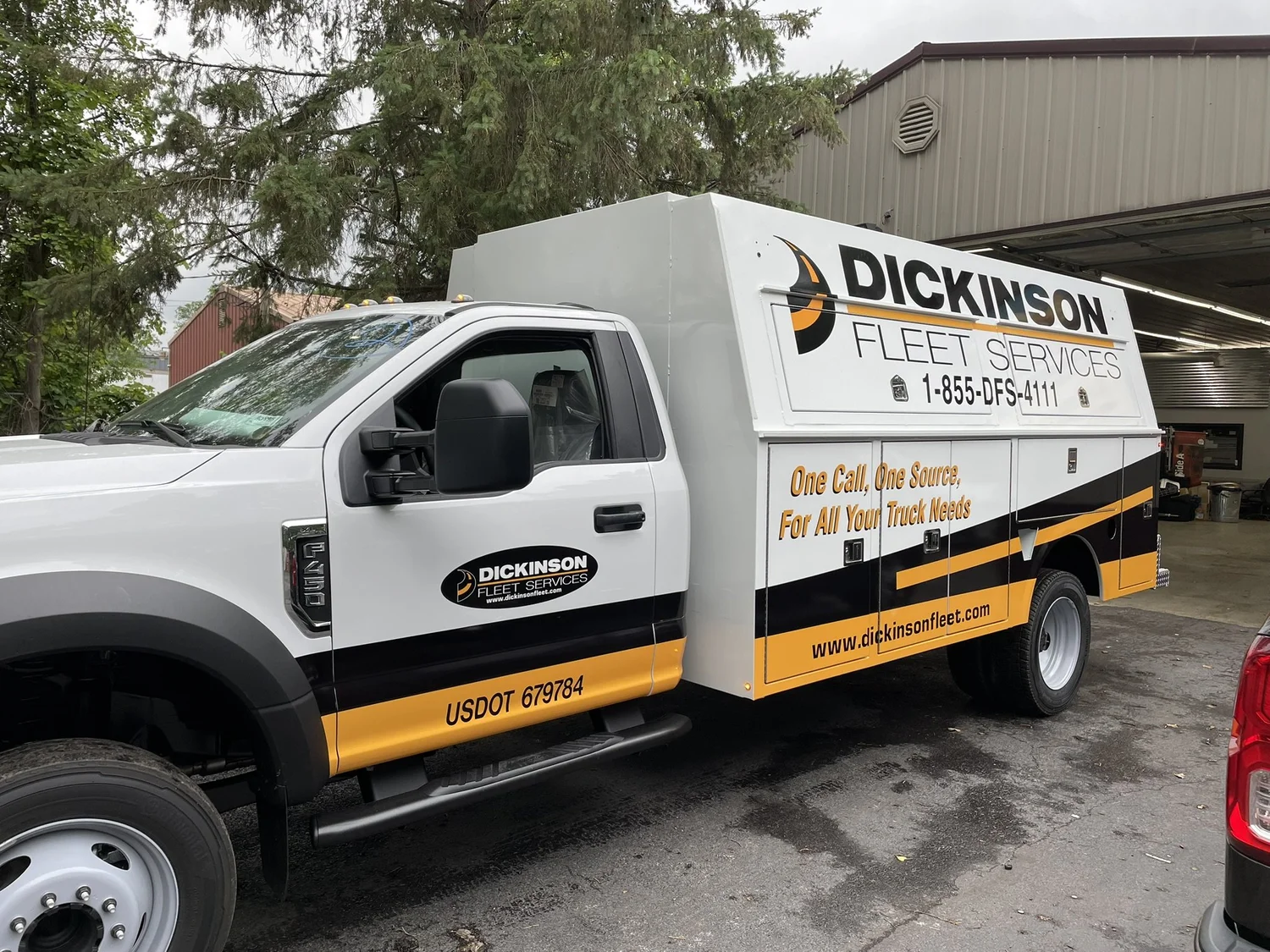 A white Dickinson Fleet Services truck with black and yellow commercial graphics